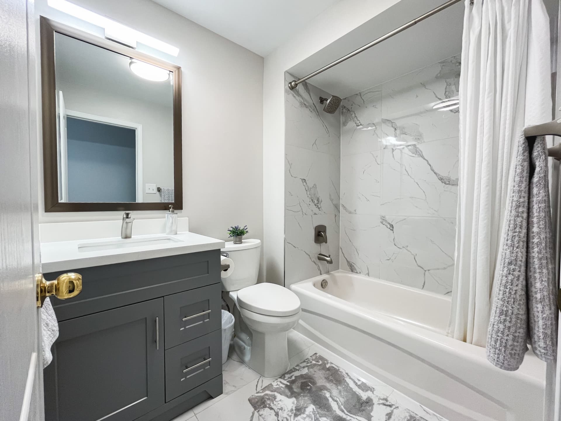 Renovated bathroom with a marble-look tiled tub surround