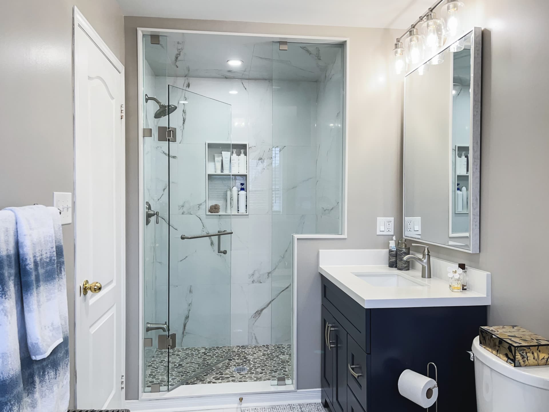 Renovated bathroom with a frameless glass shower and marble-look wall tile